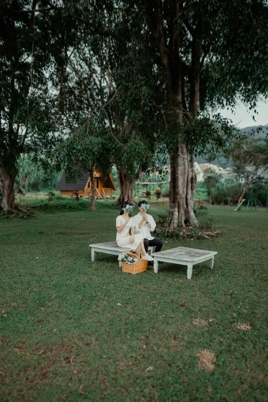 two women are sitting on a bench in the park