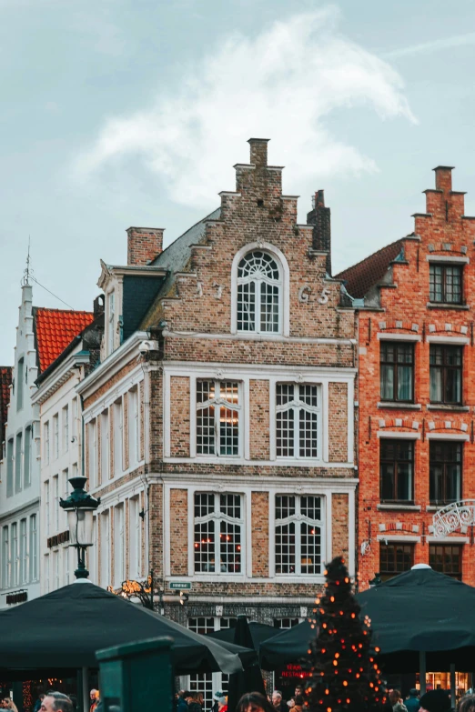 people walking by shops next to an old building with a christmas tree