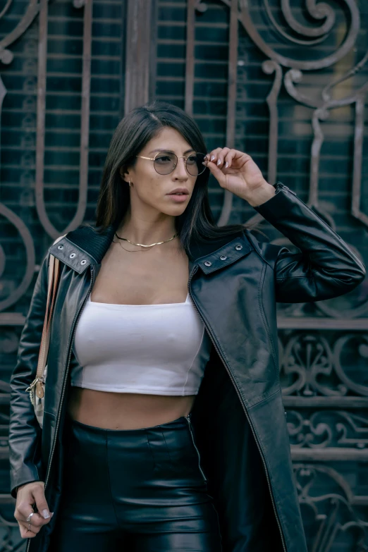 a women with black leather pants and crop top is wearing sunglasses