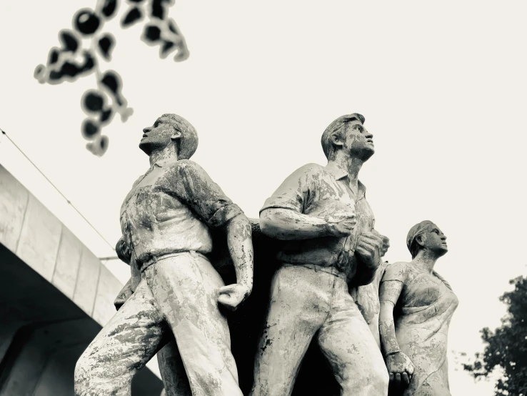 three statues of men are in the air near one another