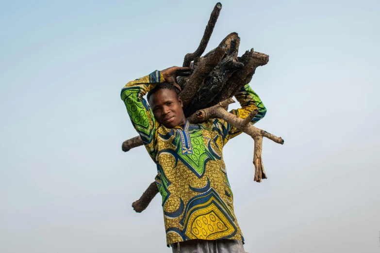 an african man carrying two large twigs across his head