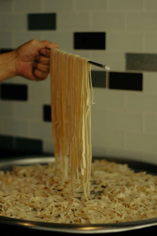 someone is adding noodles to a pan on a stove