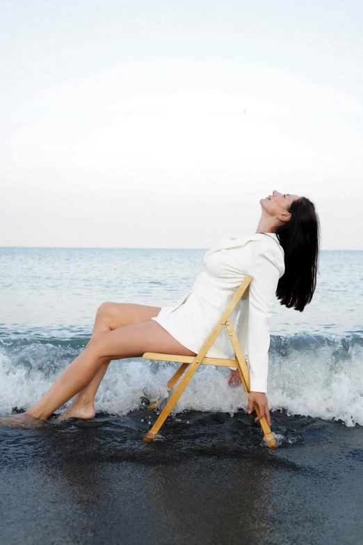 a woman sitting in a chair on the beach