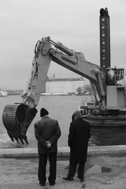 two men standing in front of an excavator