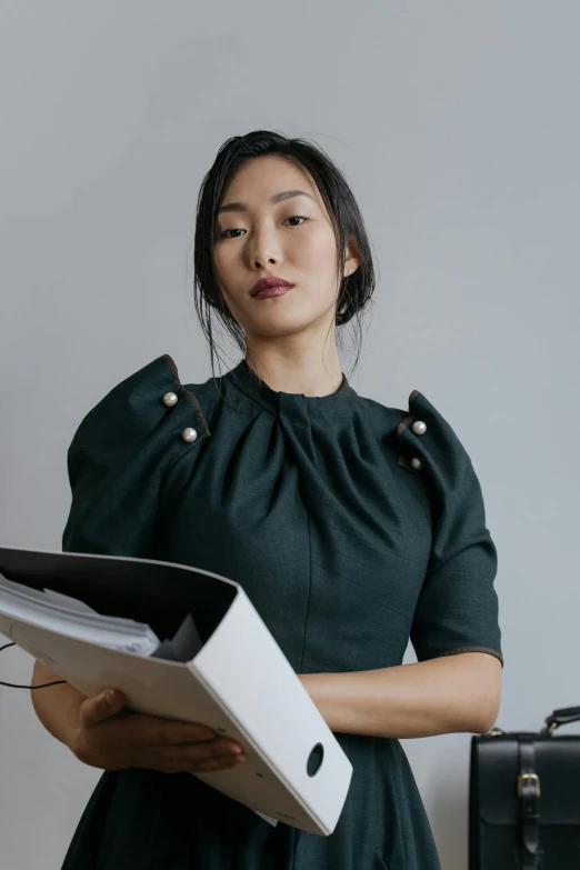 woman with black hair standing and holding book in her hands