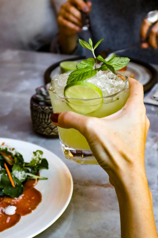 a close up of a person holding a drink near a plate