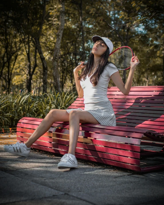 a woman sitting on a bench with a tennis racket