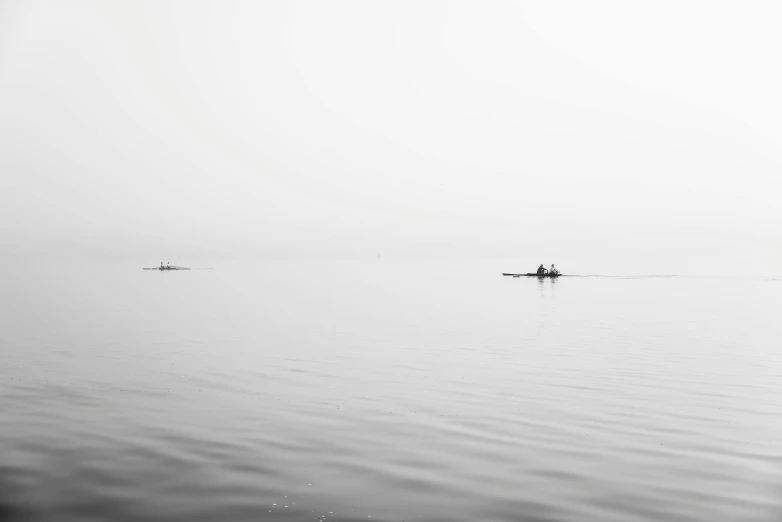 people are rowing in the calm water on their boats