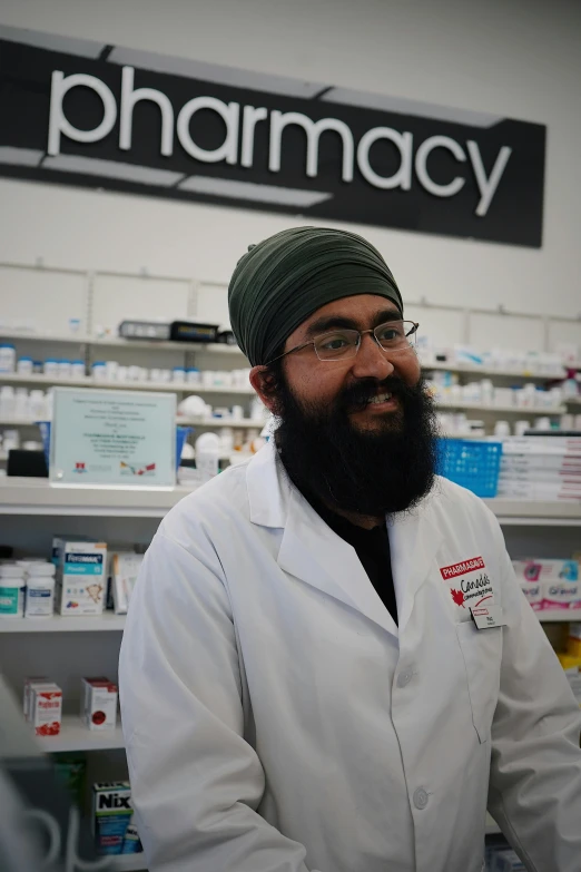 a pharmacy man wearing a long beard and wearing glasses in a pharmacy  department