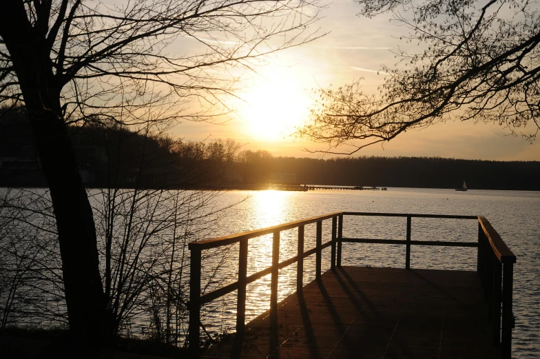 the sunset over a lake is setting and the water is still calm