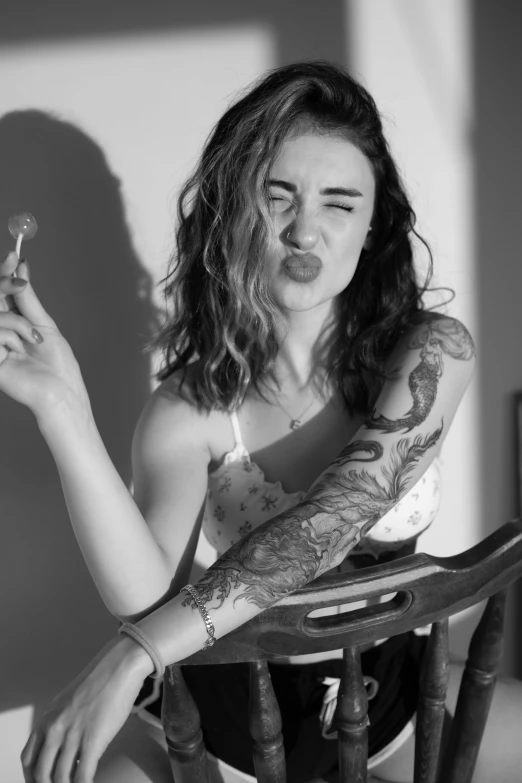 woman in white shirt sitting with tattoo holding cigarette