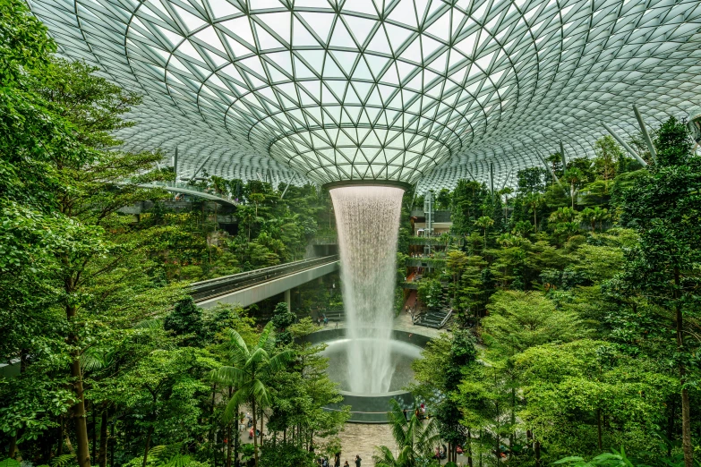 an artificial waterfall surrounded by trees inside a building