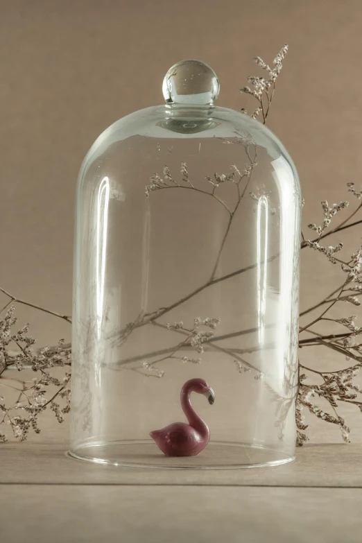 a glass bottle with water and a fake pink flamingo on the bottom