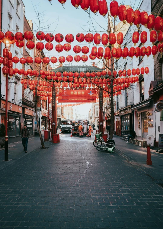 a person standing under red chinese lanterns hanging in the middle of a city