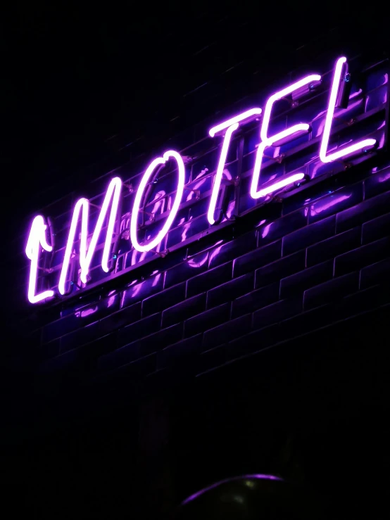 the neon sign says motel lit up against a black wall