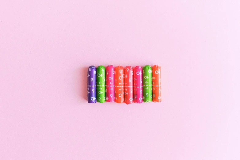 a set of eight colored markers on a pink background