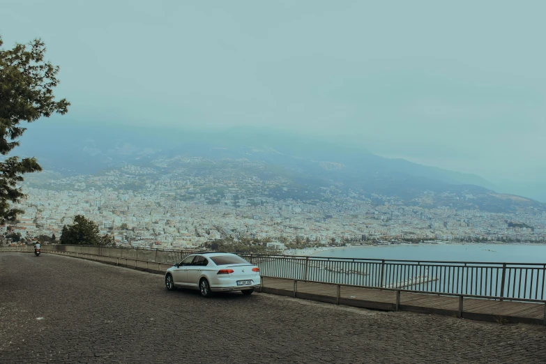 a white car driving past a large body of water