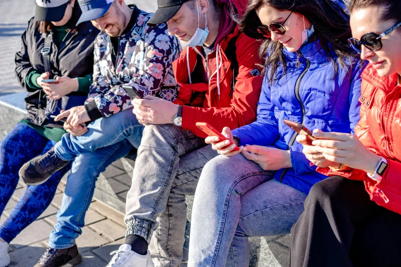 some people are sitting on the curb and using cell phones