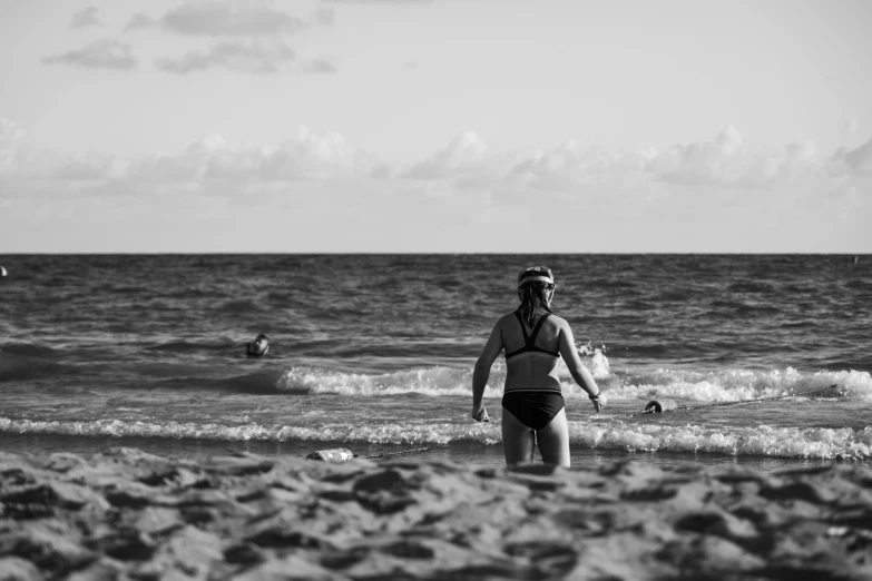 a woman in black swimsuit walking into the water