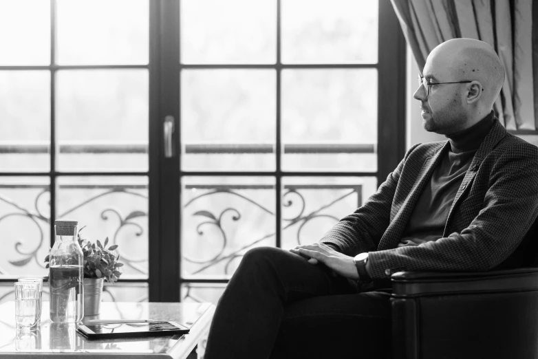 a man is sitting down with a glass of wine in his hand