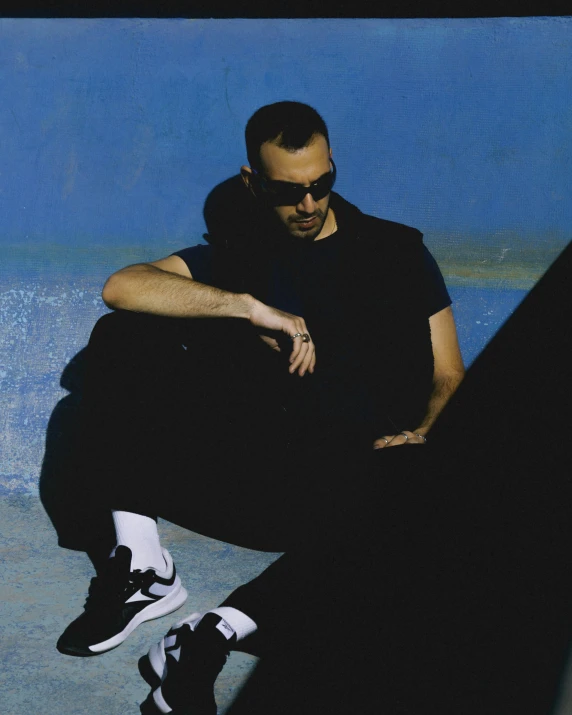 a man in black clothes is sitting on a wall