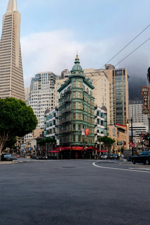 a tall tower with green top stands in the middle of the city