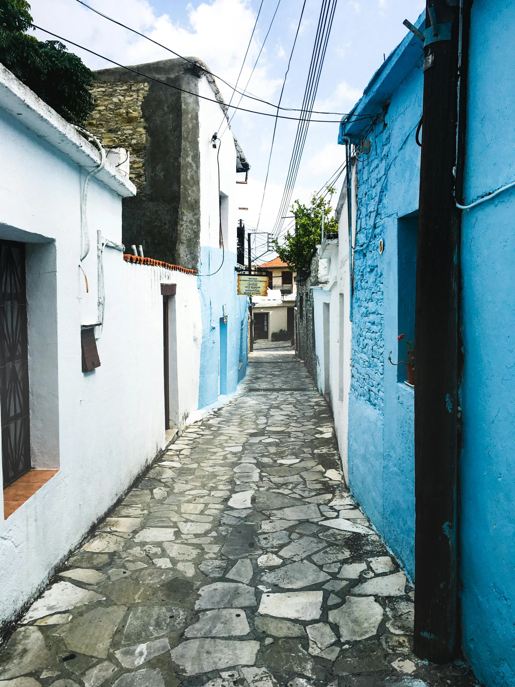 an alley in a town, with blue walls and cobblestones