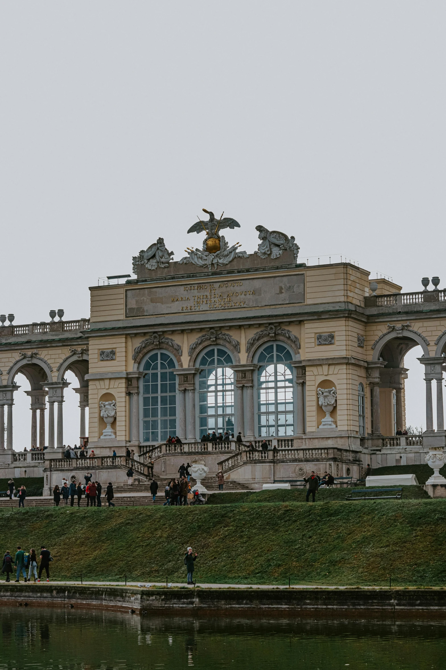 people stand in front of a large building near the water