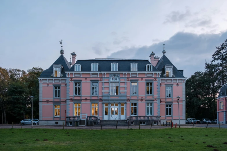 a very big pretty pink building in the middle of a field