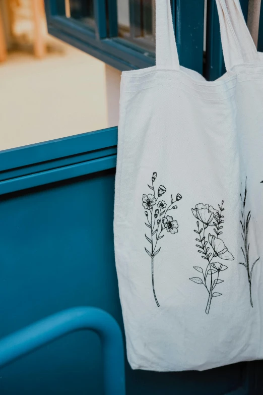 a floral tote bag sitting on a chair with blue wooden doors behind it