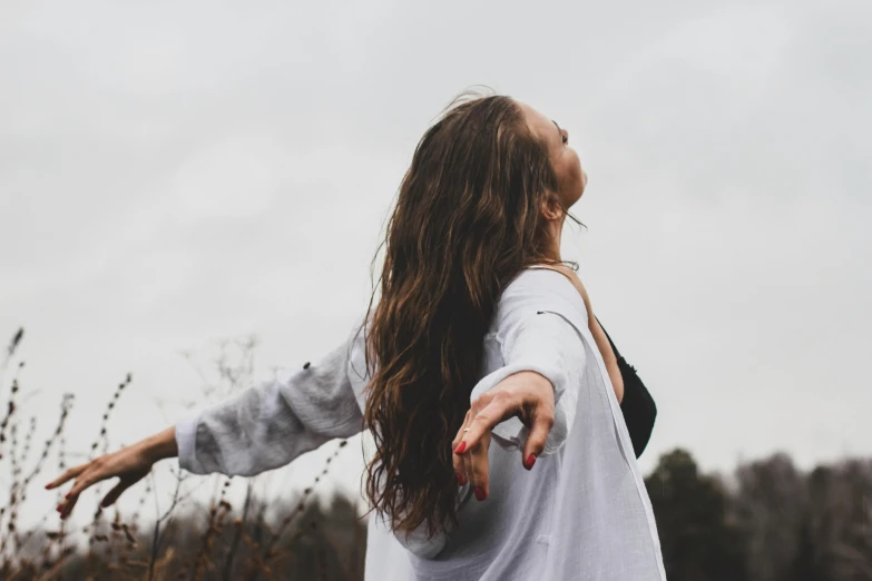 a woman with long hair and a white shirt tossing the frisbee