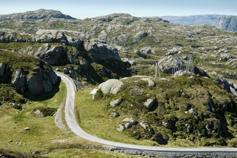 a mountain road winding in between two rocks and grass