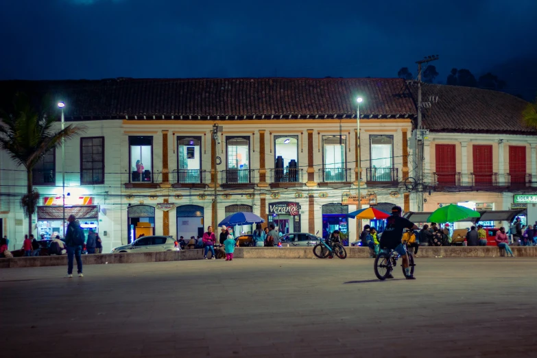 a man standing on a bicycle in front of an old building with a group of people standing nearby