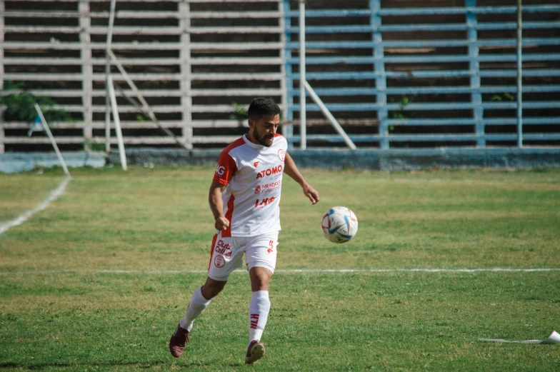 the man in red shorts is running to kick the soccer ball