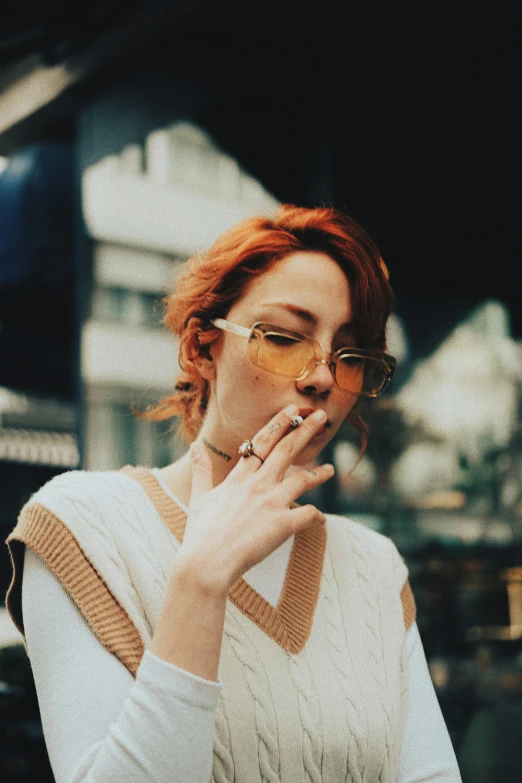 a woman smoking a cigarette outside with her hands together