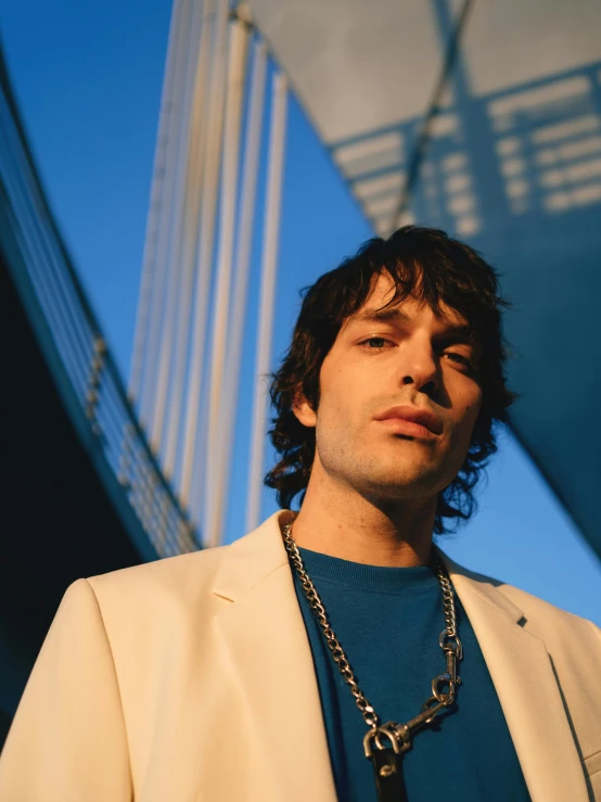 a man standing in front of a building with long chain on his neck