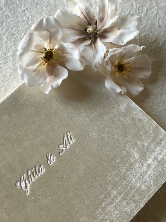 flowers and embroidered wedding guest book are sitting on the table