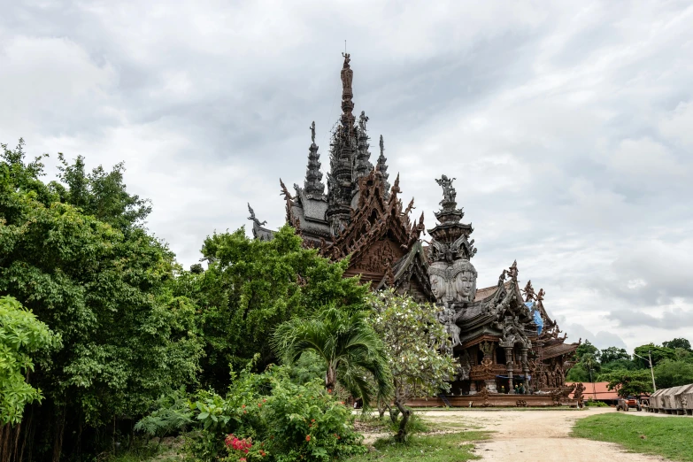 an architectural structure on a dirt road surrounded by trees