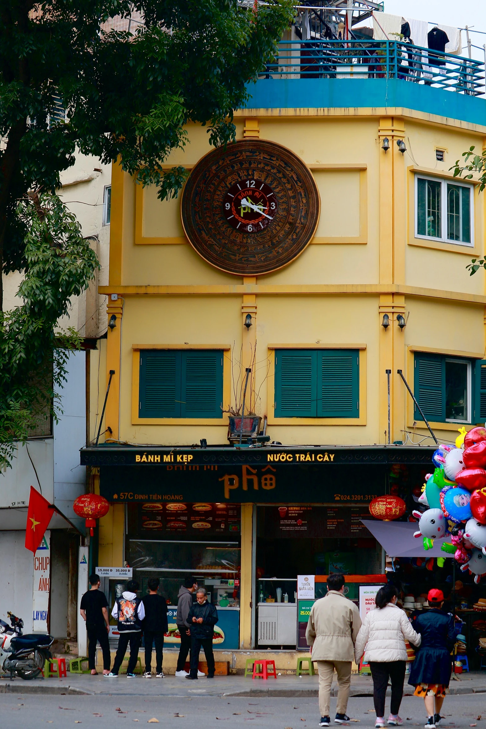 a street view of a multi - story building with an outdoor clock on the front