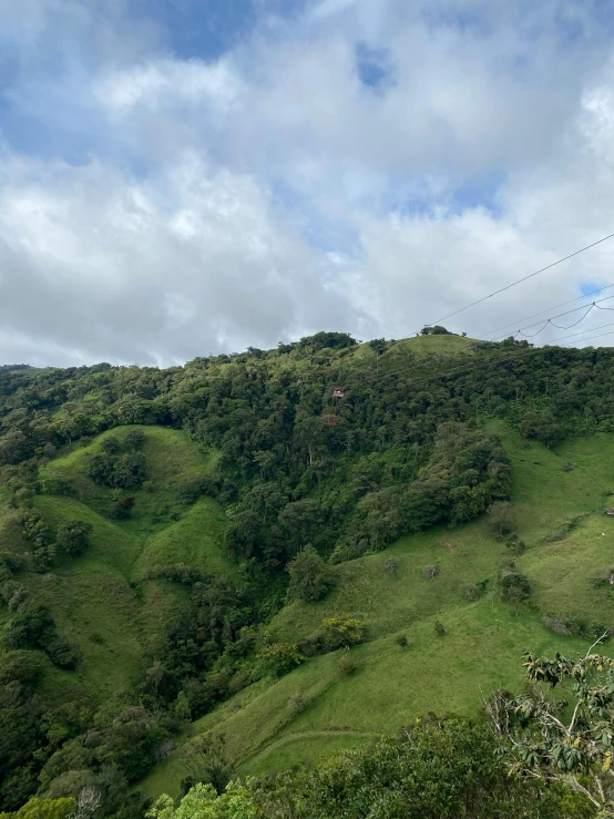 a hill covered with green grass under a blue cloudy sky