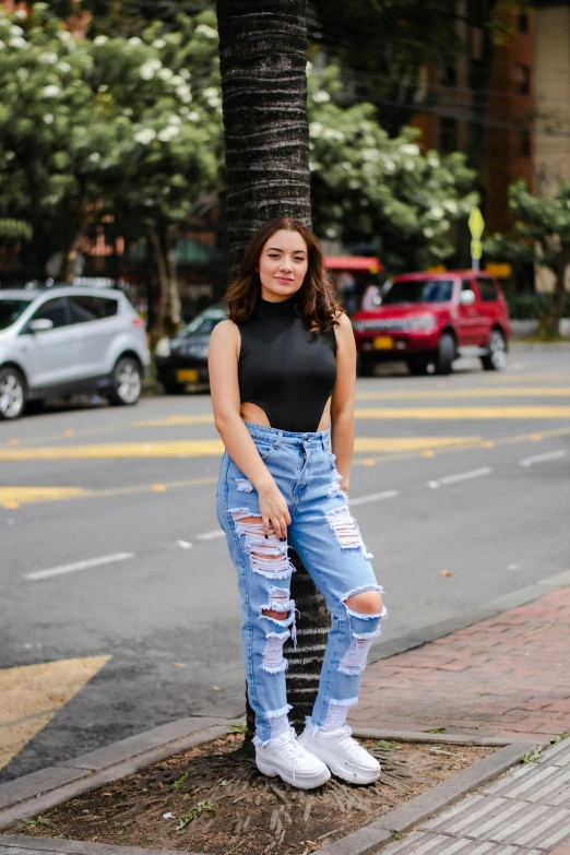 a woman with ripped jeans poses for a po