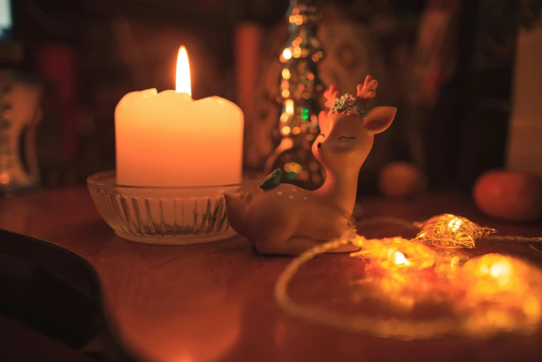 a small lighted candle sits beside a deer figurine