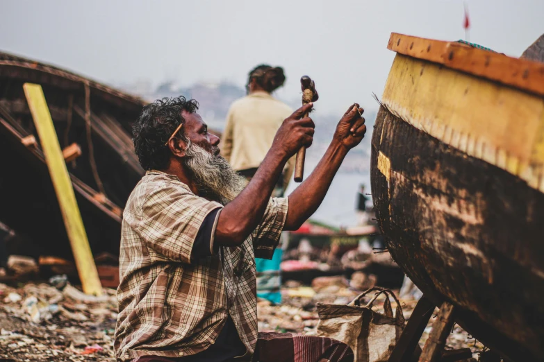 a man fixing an old boat near another man