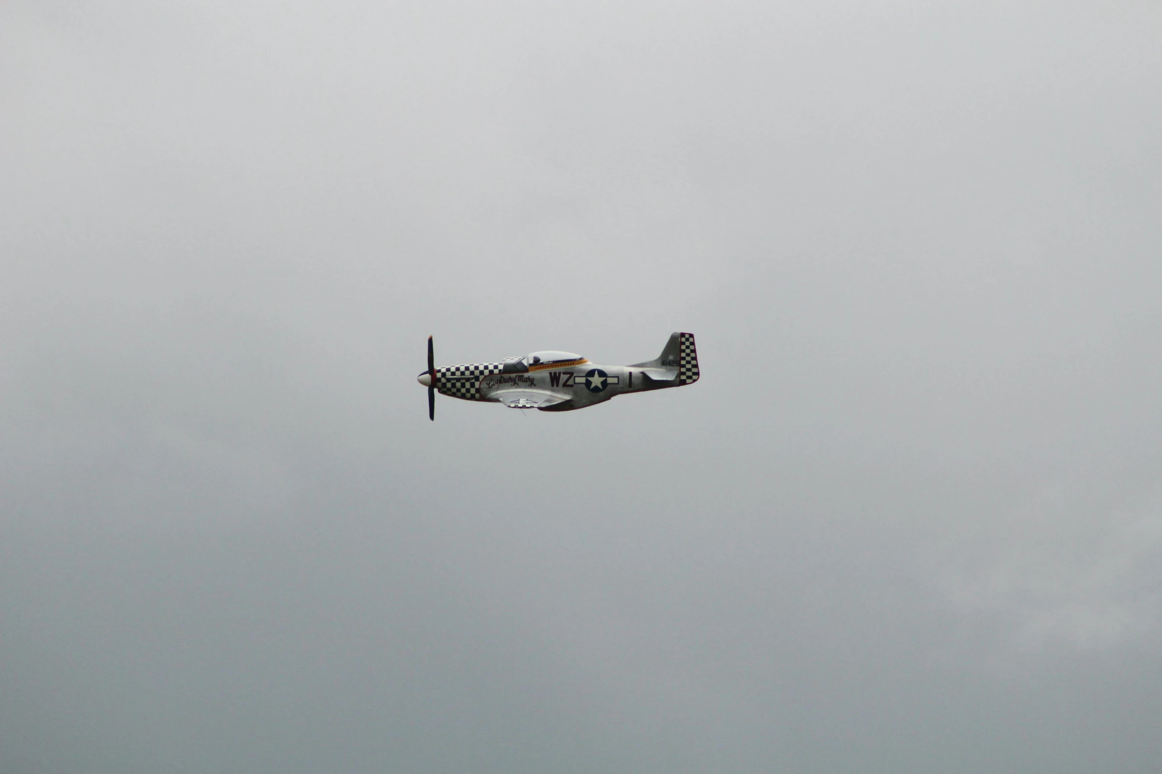 a small propeller plane flying in a gray sky