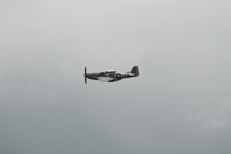 a small propeller plane flying in a gray sky