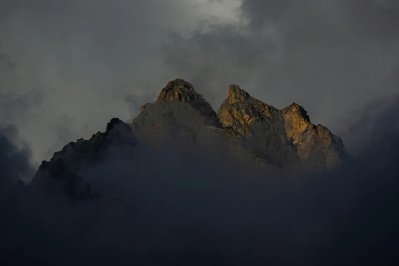 the face of a mountain surrounded by clouds