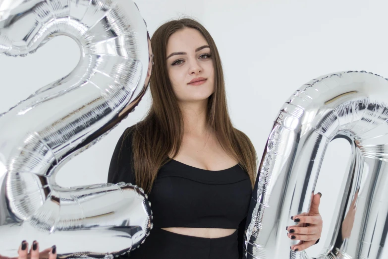 a woman holding three big balloons in front of her