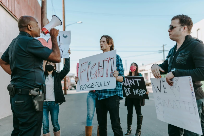 two women and one man holding protest signs in the middle of the road