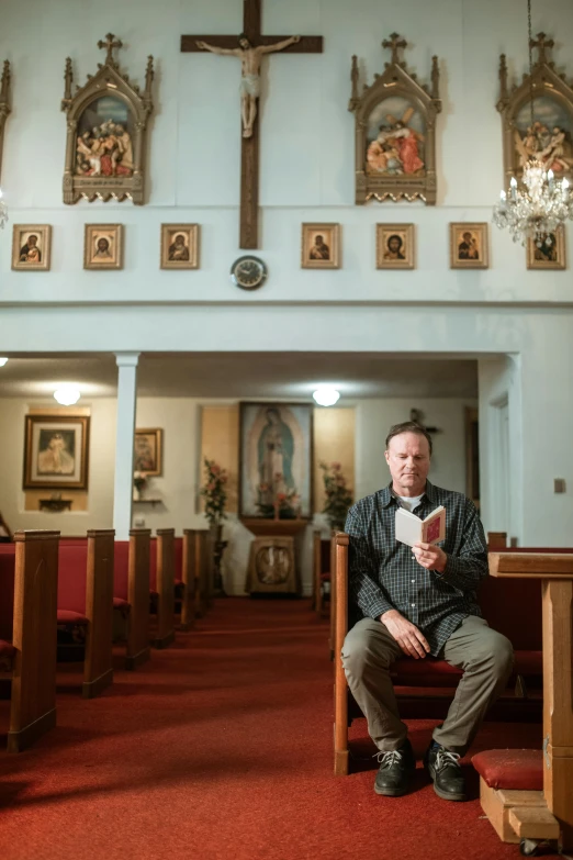 a man sitting on a bench in front of a cross