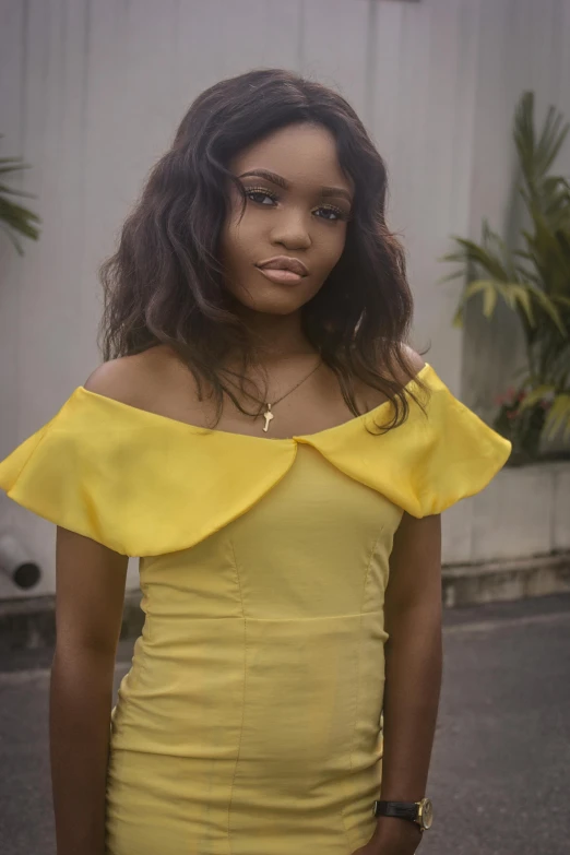 a woman wearing a yellow dress poses for the camera